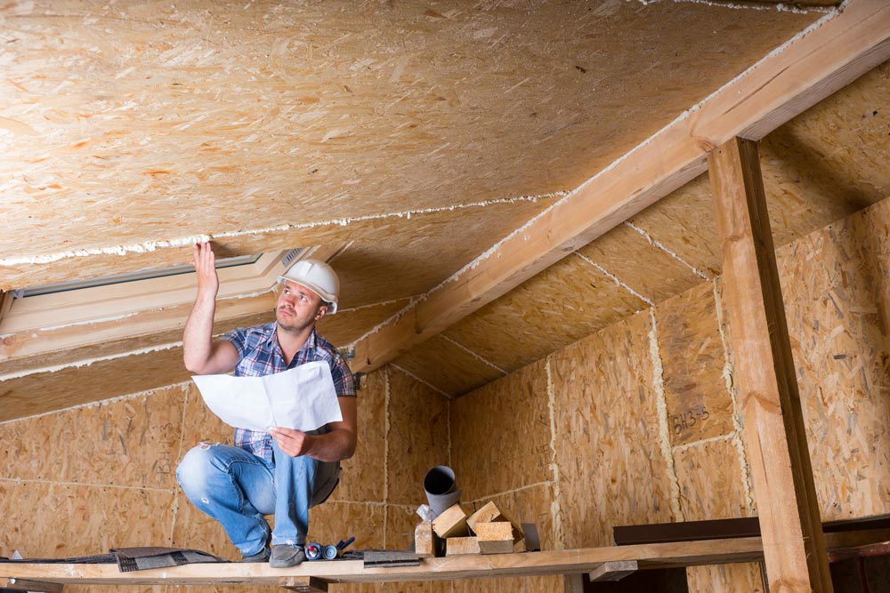 worker inspecting roof sheathing during home inspection